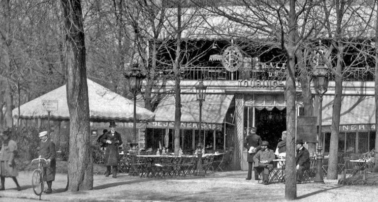 The Touring Club de France chalet in 1898, a garden restaurant among bare trees with diners at outdoor tables and a cyclist standing with a bicycle at left