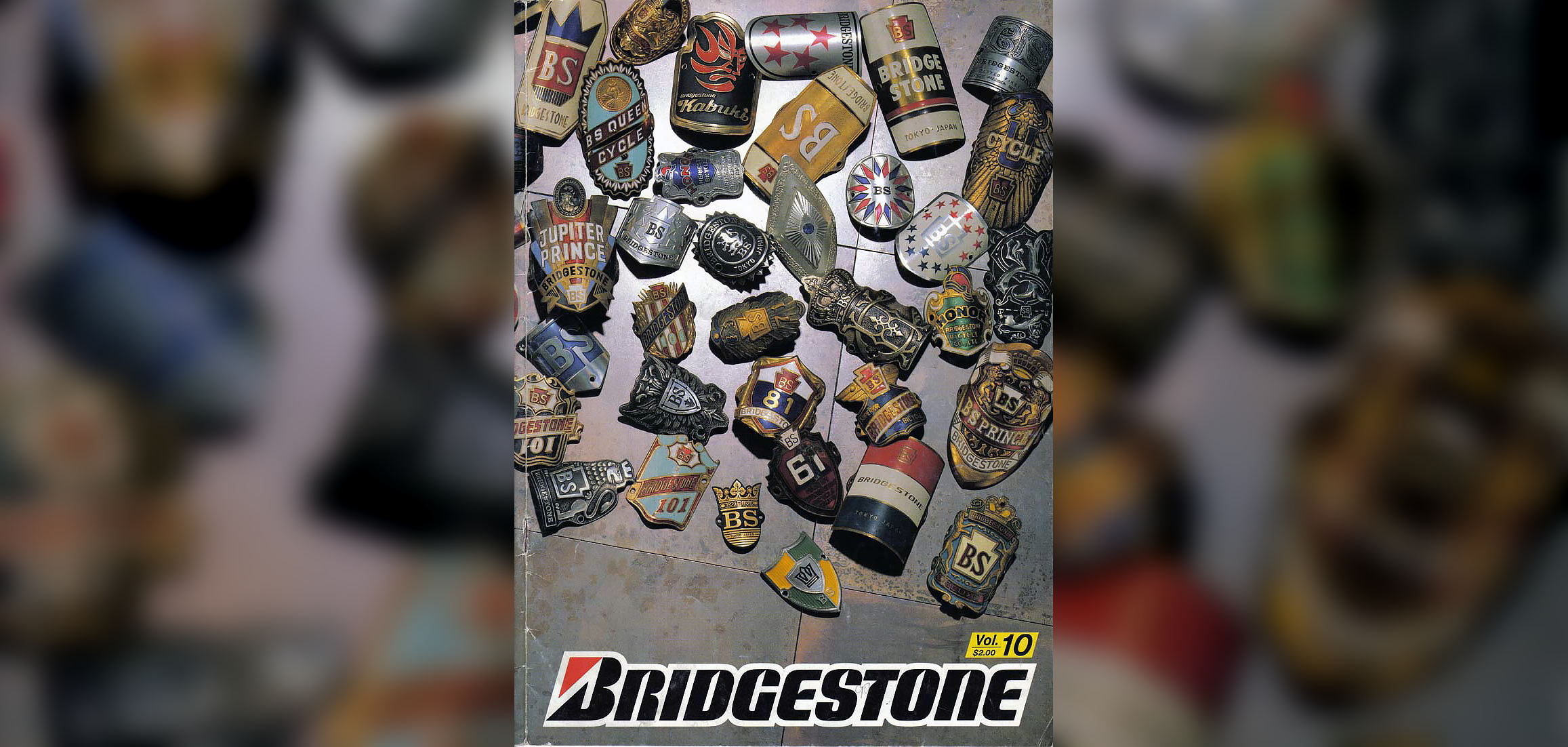 Bridgestone 1990 catalog cover photo showing metallic head badges and pins on a stone surface