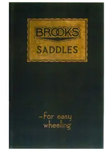 Dark green card cover blocked in gold, the word BROOKS reversed out of a gold rectangular panel with a chain-link border, SADDLES beneath it, and the handwritten-style line for easy wheeling in the lower right corner.