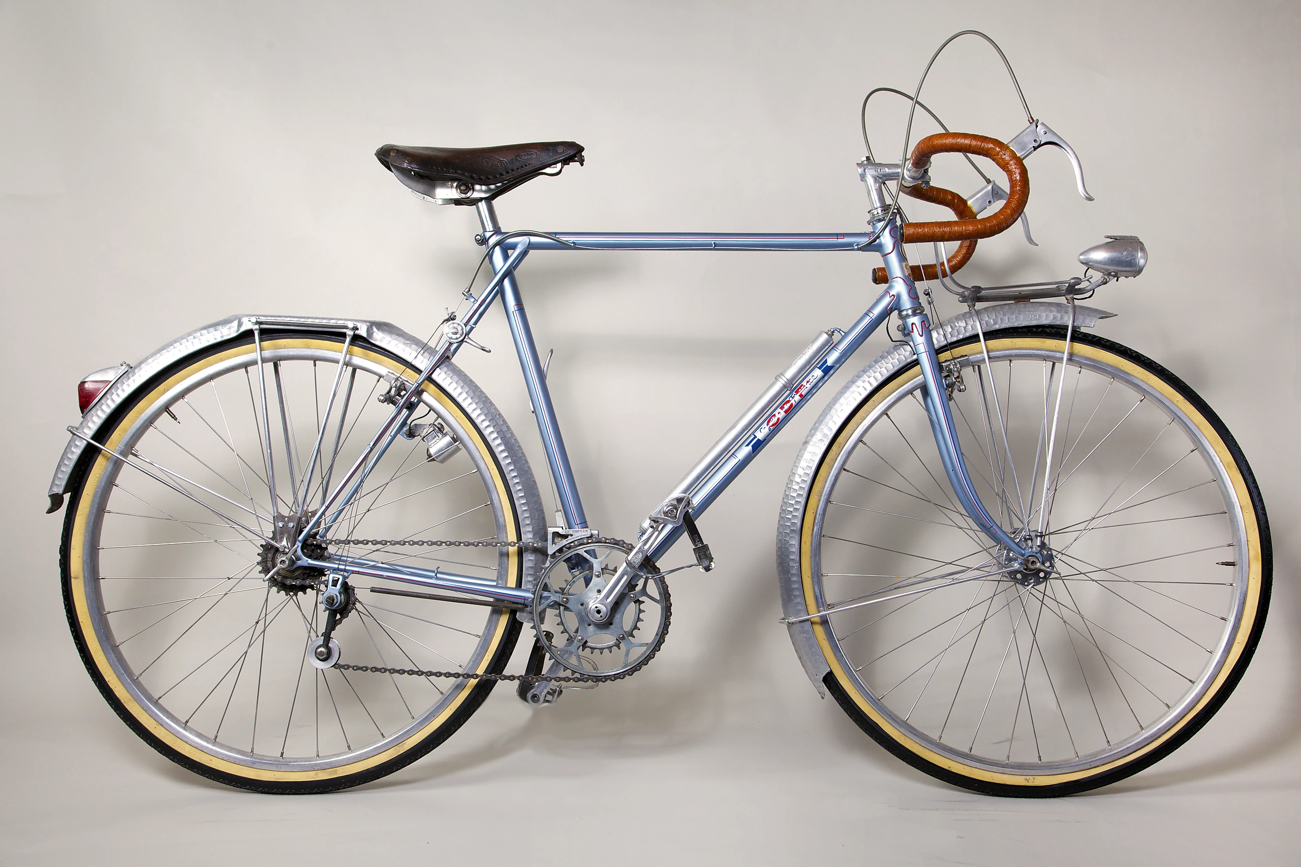 Drive-side profile of a 1948 Cycle de France concours randonneuse in pale metallic blue, with hammered Lefol fenders, a lugged alloy front rack, an alloy headlamp and 650B wheels