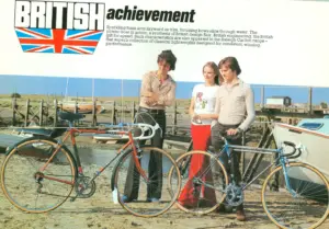 A Raleigh Carlton catalog spread: two riders and a woman standing on wet sand between an orange and black Carlton Ten and a chromed blue Carlton, cabin cruisers propped on the mud behind them, and the headline BRITISH achievement over a Union flag shield at the upper left.