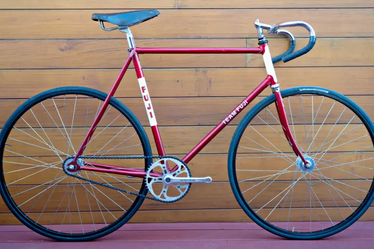 Drive-side profile of a 1970s Team Fuji track bicycle in metallic red with white head tube and seat tube panels, fitted with a Sugino crankset, Araya rims and a Palace leather saddle