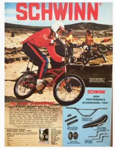 Advertisement showing a rider in red racing leathers jumping a red Schwinn Scrambler at a dirt motocross track, with an accessories panel and a coupon for the 1976 Schwinn Bicentennial Bike Book