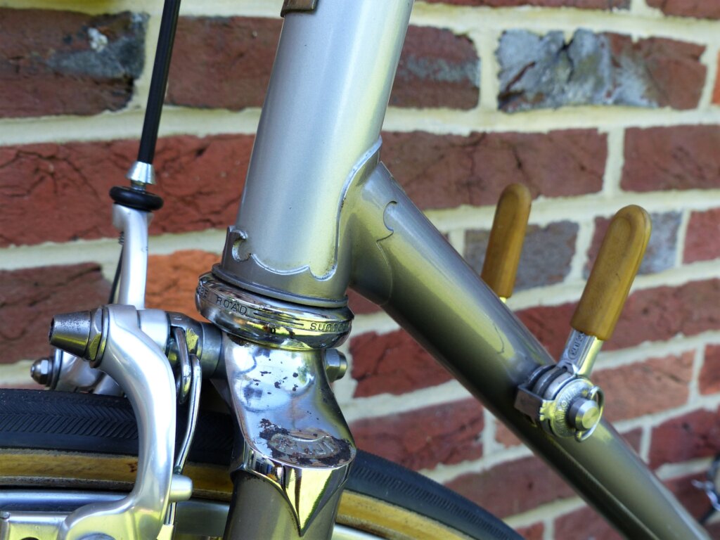 Close-up of the head tube and down tube junction of a 1979 Fuji Professional, showing shaped lug cutwork, a SunTour Superbe Road headset and a chrome fork crown