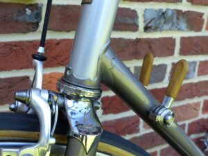 Close-up of the head tube and down tube junction of a 1979 Fuji Professional, showing shaped lug cutwork, a SunTour Superbe Road headset and a chrome fork crown