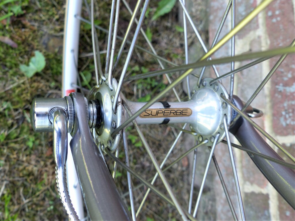 Polished SunTour Superbe front hub with gold decal, laced to a wheel with a quick release skewer visible at the fork end