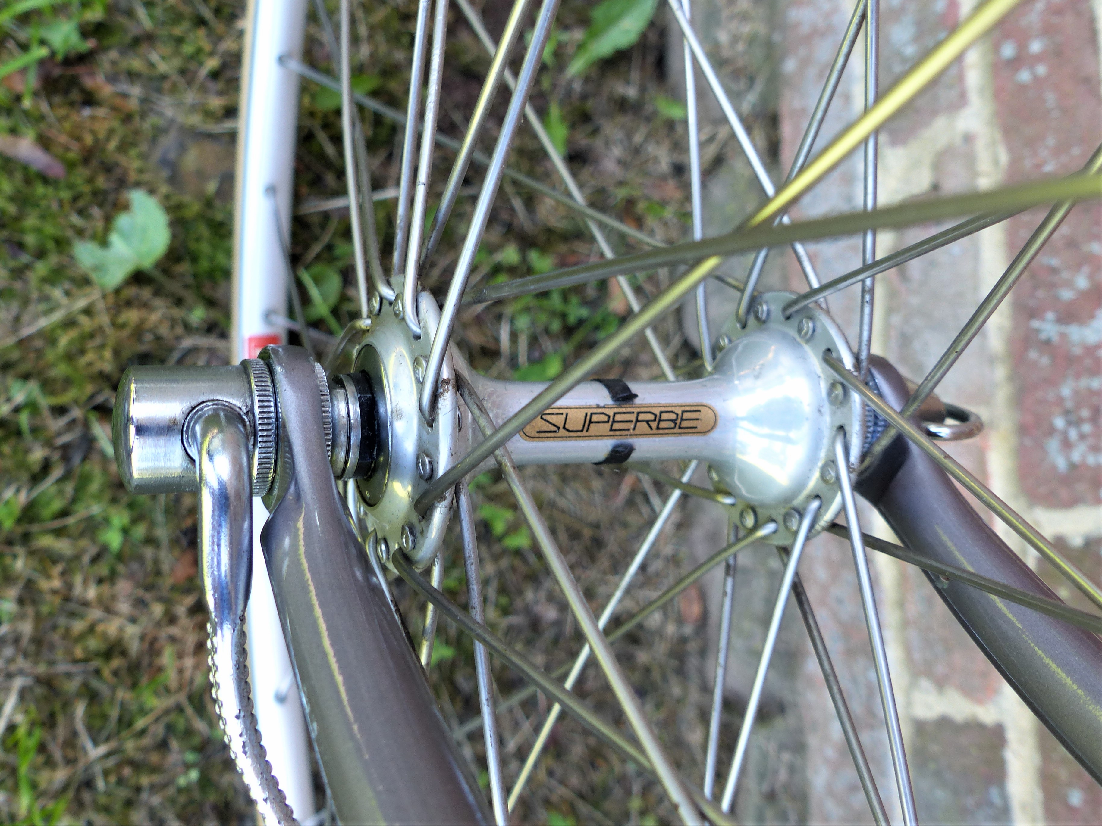Polished SunTour Superbe front hub with gold decal, laced to a wheel with a quick release skewer visible at the fork end
