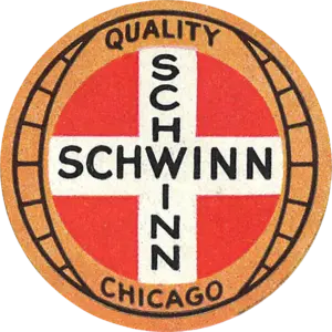 Circular Schwinn badge with a red field, a white cross lettered SCHWINN twice, and a tan outer ring reading QUALITY and CHICAGO