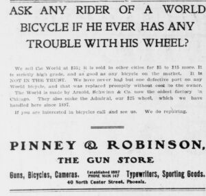Newspaper advertisement headed ASK ANY RIDER OF A WORLD BICYCLE IF HE EVER HAS ANY TROUBLE WITH HIS WHEEL?, with body text stating IT IS NOT IN THE TRUST and naming Arnold, Schwinn & Co. of Chicago and the Admiral at $25, above the dealer imprint PINNEY & ROBINSON, THE GUN STORE, 40 North Center Street, Phoenix.
