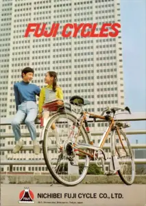 Catalog cover photographed against a high-rise office block, two young people seated on a railing beside a Fuji sports bicycle, under the words Fuji Cycles in red