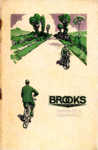 The front cover, a drawing in green, mauve and black of a country lane between hedges and trees.