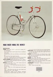 Fuji Road Racer Model The Newest in silver with red bar tape and tan brake hoods, photographed on a gray backdrop above its specification.
