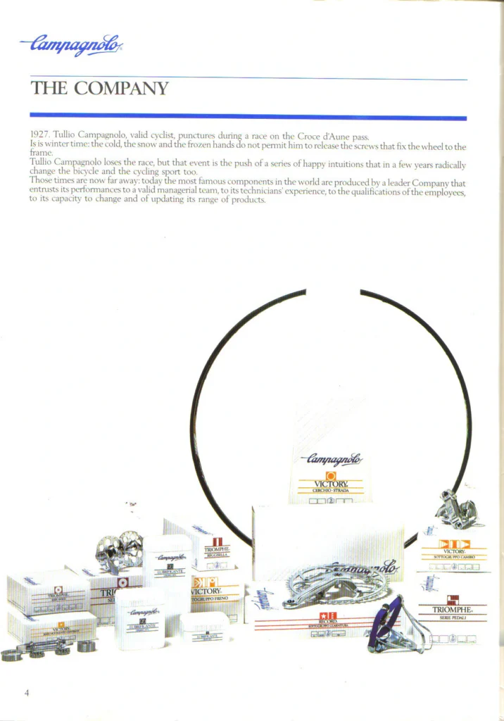 A catalog page headed The Company under the Campagnolo script logo, with a short text on Tullio Campagnolo's 1927 puncture above a photograph of boxed Campagnolo components and a black rim.