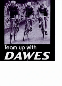 The front cover: three riders in Dawes jerseys climbing a walled lane on racing bicycles, photographed, above the title in white on a black panel.
