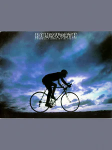 The front cover: a photograph of a rider on a racing bicycle, in silhouette against a blue and violet clouded sky, under the outlined HOLDSWORTH wordmark.